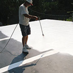 Man spraying roof with coating
