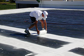 Man coating a roof with white paint