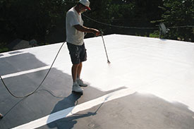 Man spraying roof with coating